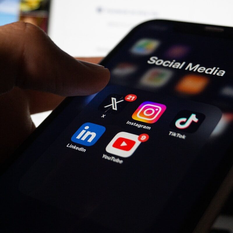 A person holding a smart phone with social media on the screen