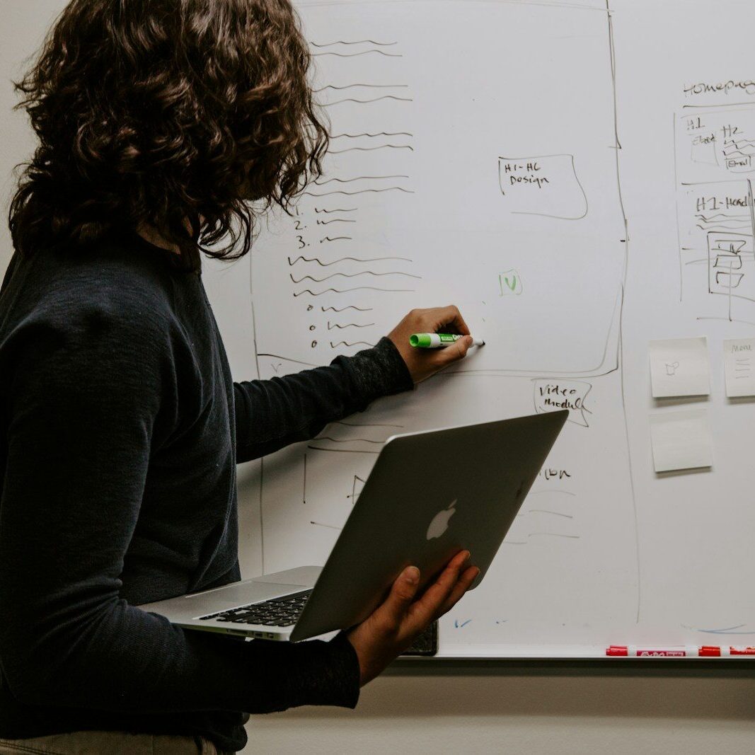 man wearing gray polo shirt beside dry-erase board